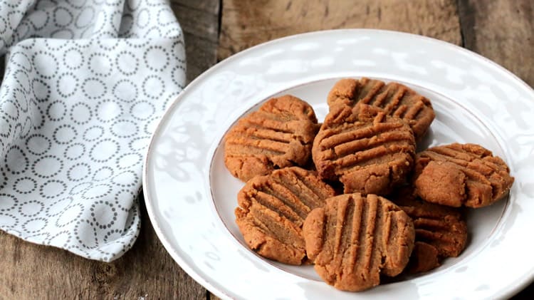 Une pile de biscuits au beurre d'arachides sur assiette blanche et planche de bois