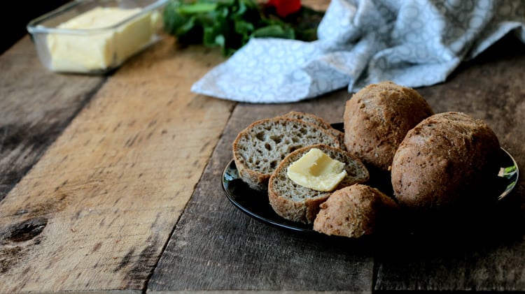 Assiette de petits pains ronds avec un carré de beurre sur planche de bois