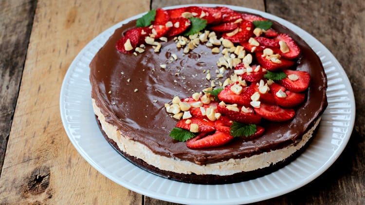 Vue à angle du gâteau frais au chocolat garni de fraises coupées et feuilles de mélisse sur assiette blanche