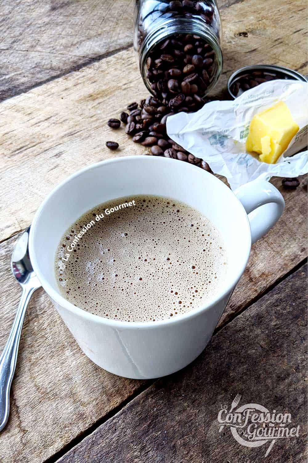 Tasse de café gras keto mousseux avec pot de grains de café et bâtonnet de beurre sur planche de bois